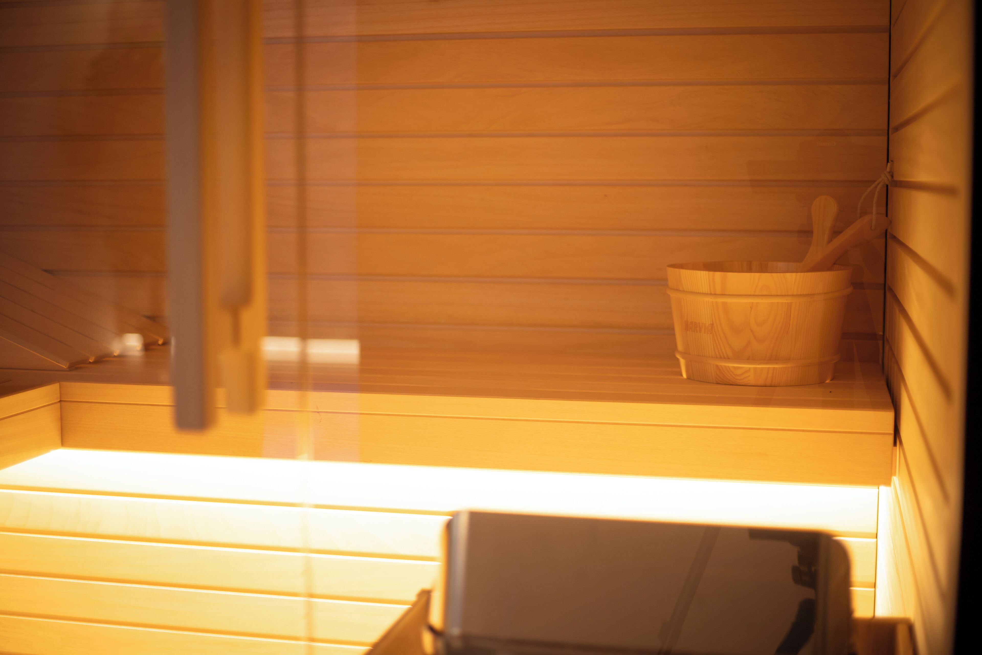 A sauna with wooden benches and a wooden bucket with a wooden spoon.