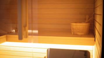 A sauna with wooden benches and a wooden bucket with a wooden spoon.