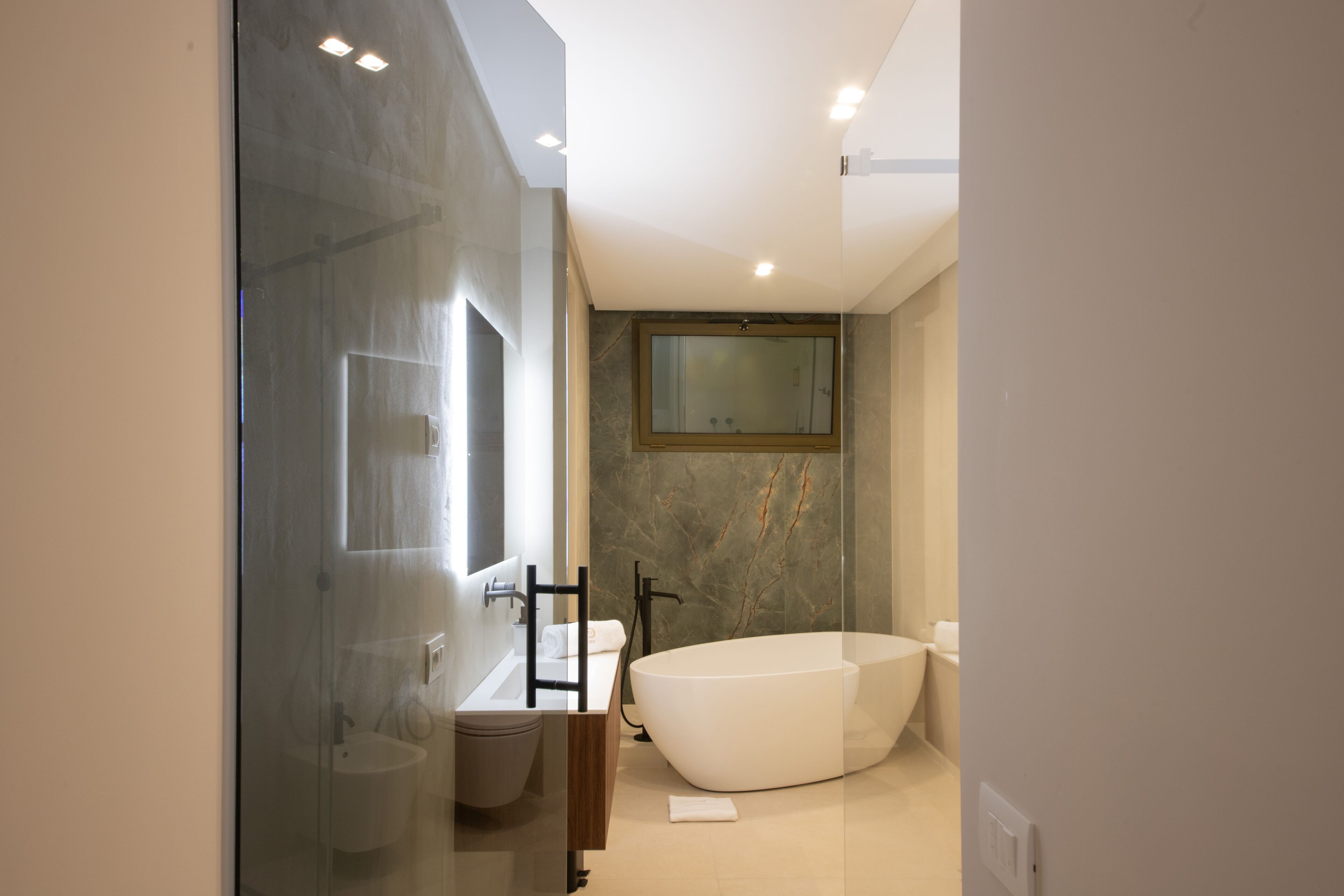 Un baño moderno con una bañera independiente, cabina de ducha con paredes de vidrio y tocador con espejo.
