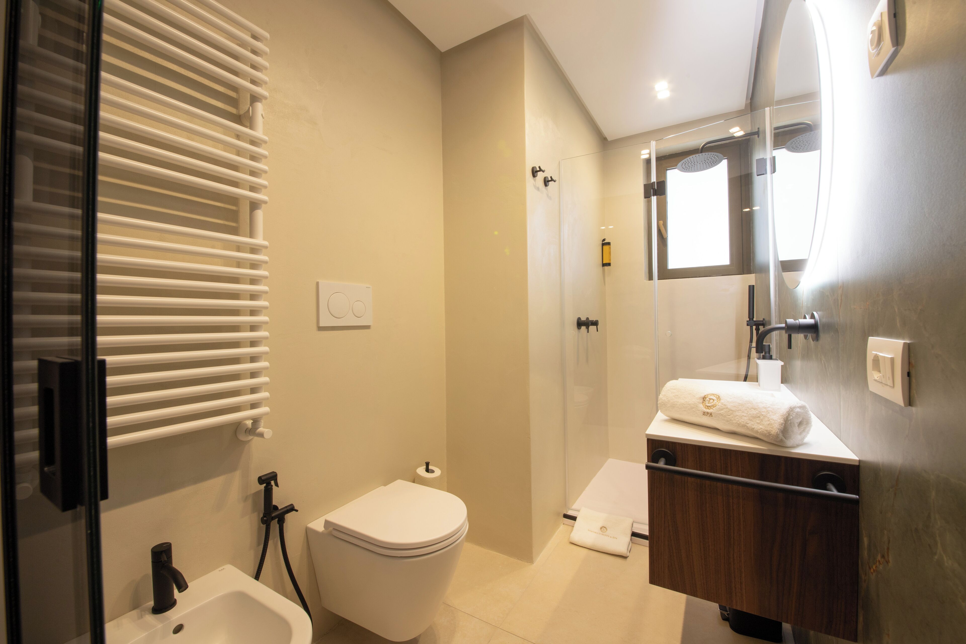 Une salle de bain moderne équipée de toilettes, d’un bidet et d’un lavabo avec une serviette.