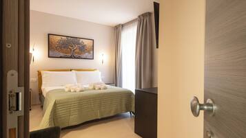 A hotel room with a bed, a painting on the wall, a door, and a light fixture.
