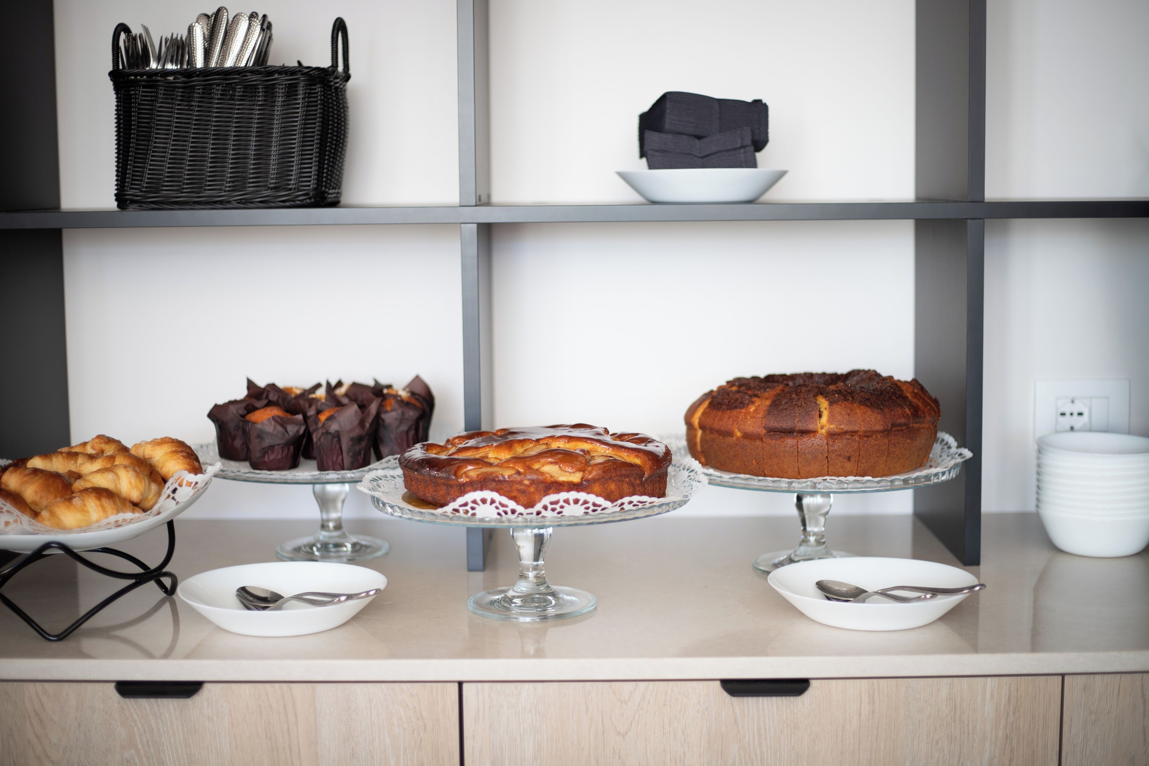 A kitchen counter with various baked goods displayed on glass stands.