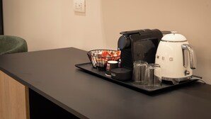 A coffee station with a coffee maker, a kettle, a basket with coffee pods, and a tray with cups and a thermos. - Dimore d'Elite e Spa (Monopoli)