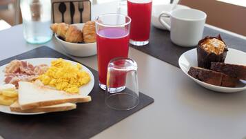 Una mesa de desayuno con cruasanes, huevos revueltos, tostadas y un muffin.