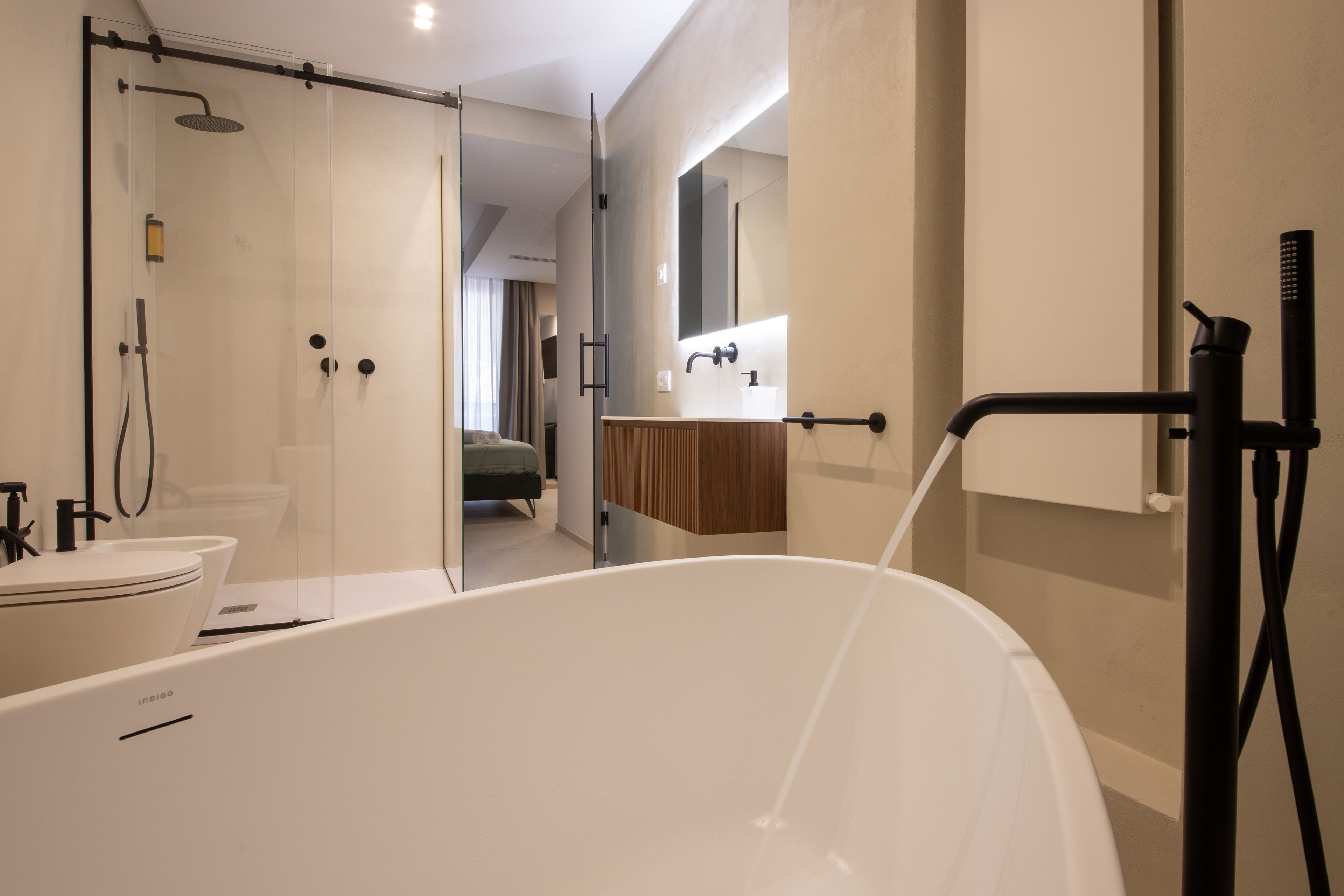 A modern bathroom with a freestanding bathtub, a glass shower enclosure, and a vanity with a mirror.