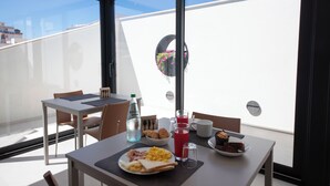 A breakfast table with croissants, eggs, and juice on a balcony with a clear view of the sky and buildings. - Dimore d'Elite e Spa (Monopoli)