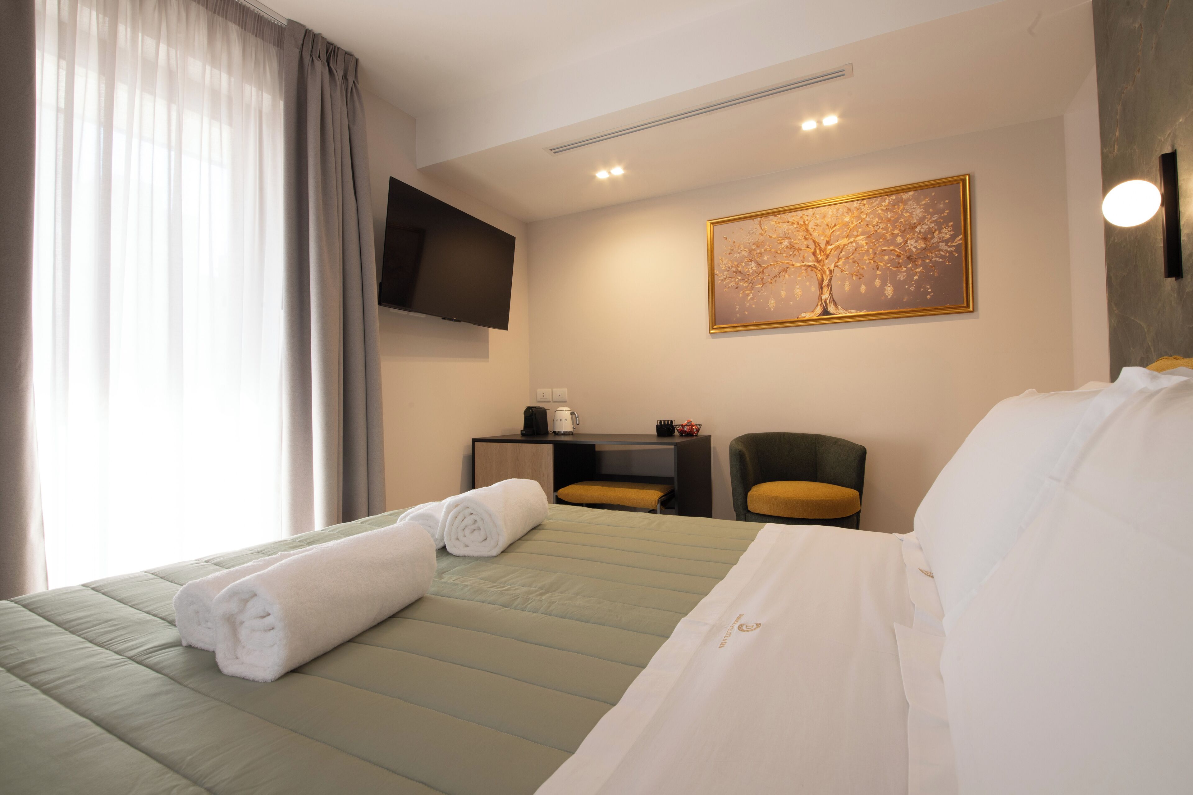 Une chambre d’hôtel avec un lit, un bureau et une chaise, un téléviseur à écran plat et un tableau au mur.