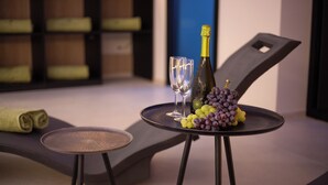 A modern room with a lounge area featuring a table with a bottle of champagne, two glasses, and a bunch of grapes. - Dimore d'Elite e Spa (Monopoli)
