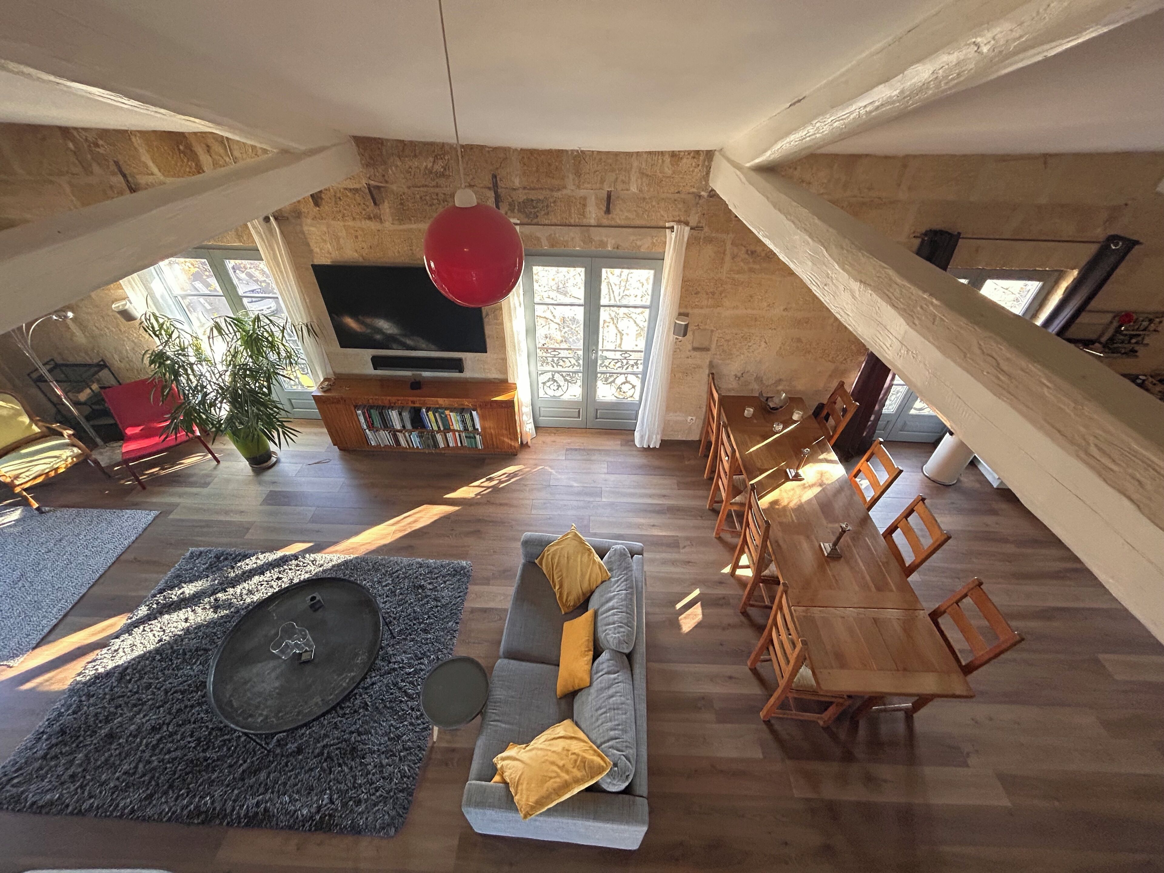 Un vaste espace de vie comprenant une table à manger en bois, un canapé et un téléviseur fixé à un mur en pierre.