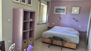 A bedroom with a bed, a wooden wardrobe, a small table with a vase, and a window with curtains. - Cozy La Lavanda Studio Apartment with private terrace and infinity pool (Merana)