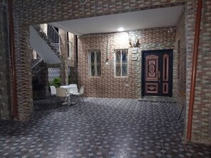An indoor area with a patterned floor, a staircase, a door with decorative panels, and a small table with chairs. - Perfect 3-bedroom apartment with AC in delightful Serrekunda (Serrekunda)