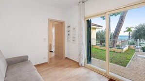 Een moderne kamer met een bank, een schuifdeur naar een buitenruimte en een houten vloer.