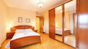 A bedroom with a wooden bed, bedside tables, a mirror, and a radiator.