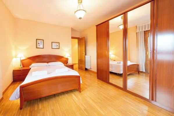 A bedroom with a wooden bed, bedside tables, a mirror, and a radiator.