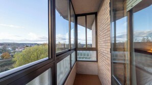 A narrow balcony with large windows, a tiled floor, and a brick wall.