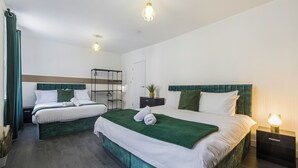 A hotel room with two beds, a wardrobe, a nightstand, and a ceiling light fixture. - Station Side Sanctuary - 2BR Central Brighton Stay (Brighton and Hove)