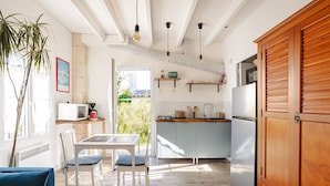 A modern kitchen with white cabinets, a wooden cabinet, and a dining area with a table and chairs.
