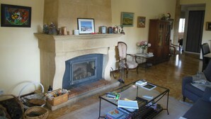 Una sala de estar con chimenea, una mesa de centro de vidrio y un sofá azul.