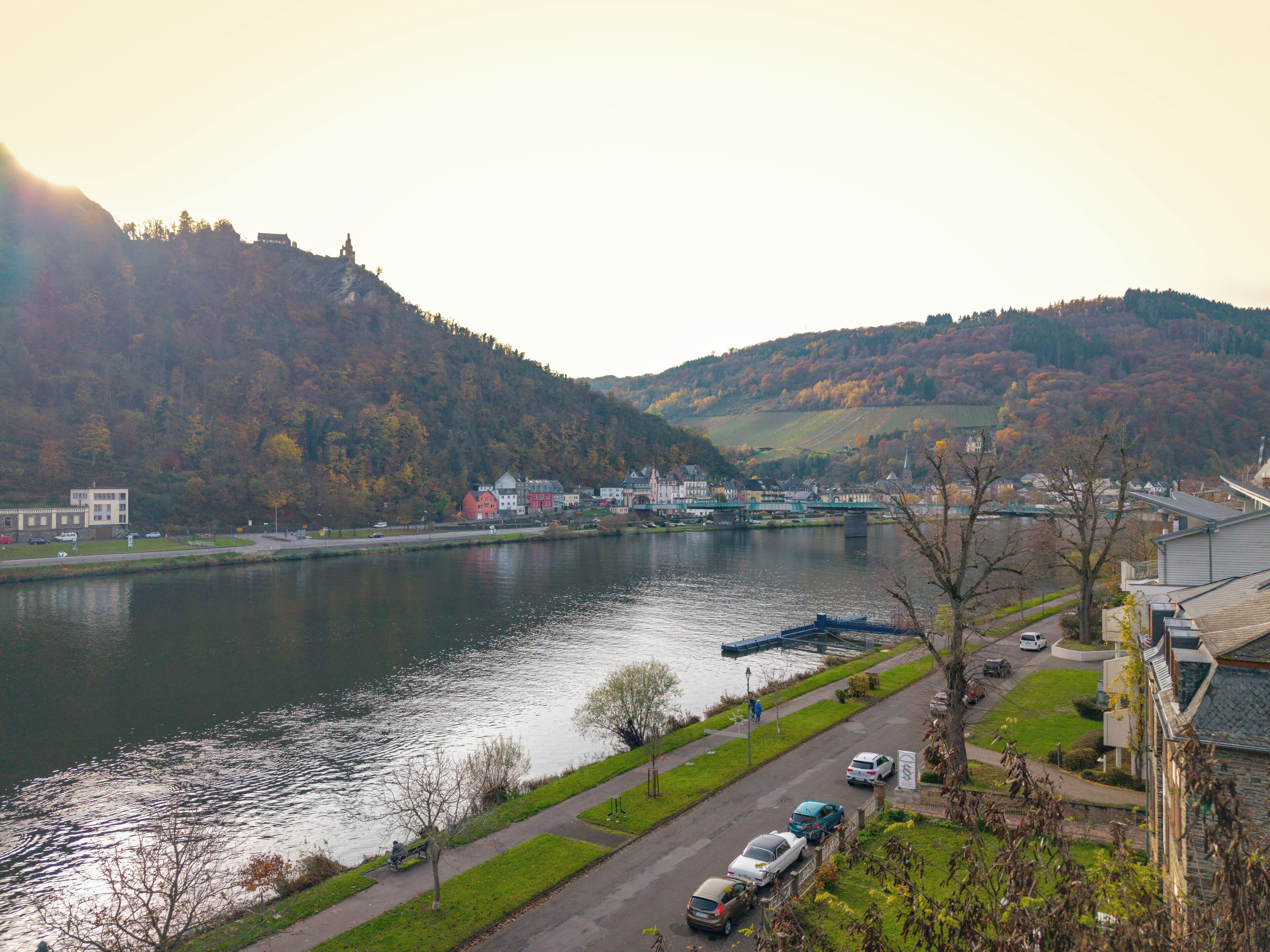 Une vue sur la rivière, avec des bâtiments, un pont et une colline en arrière-plan.