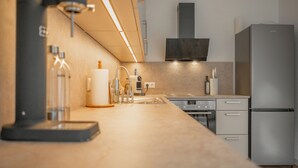 Una cocina moderna con un refrigerador de acero inoxidable, un horno empotrado y una campana extractora.