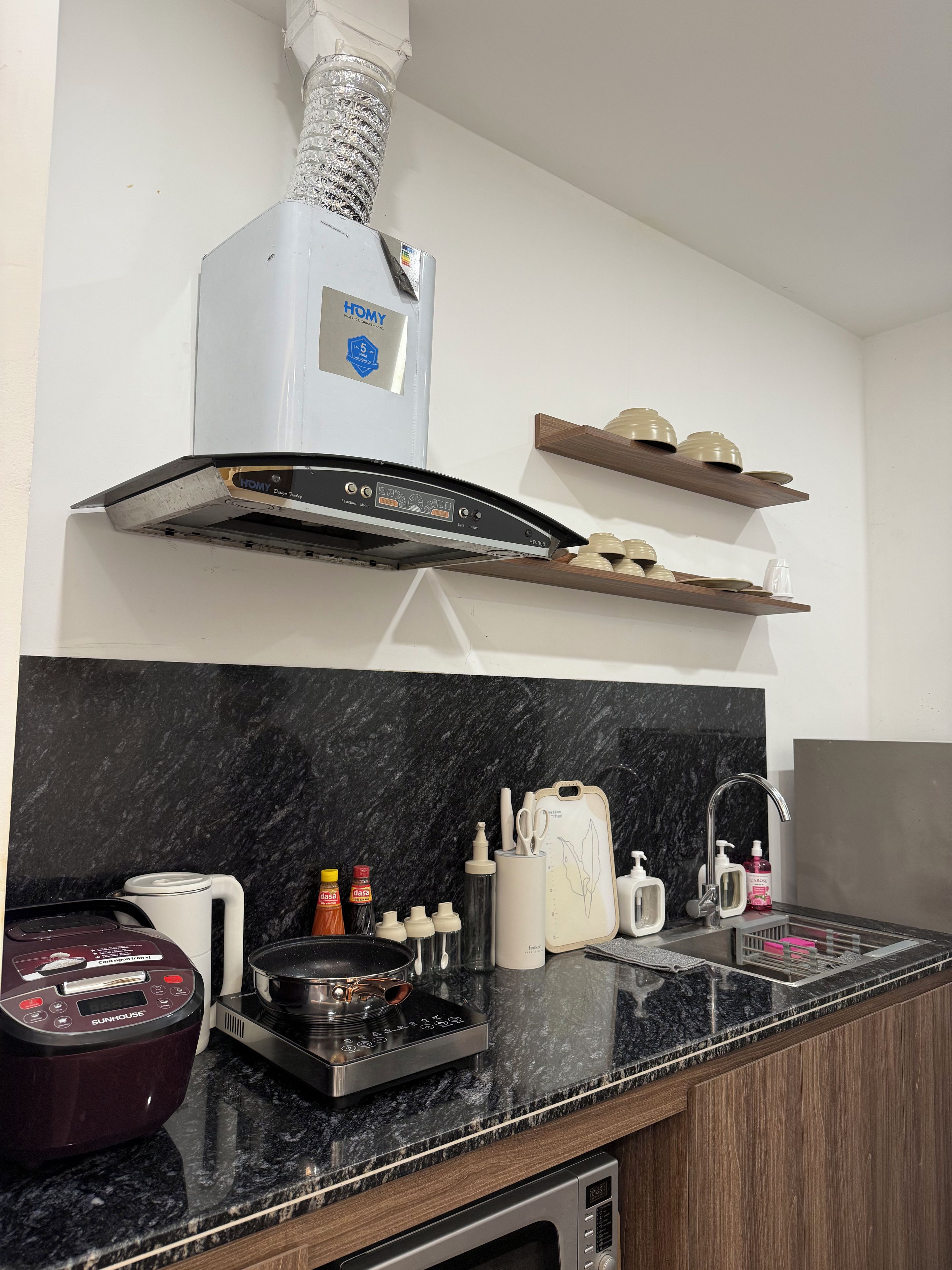 Una cocina moderna con horno empotrado, campana extractora y pileta de acero inoxidable.