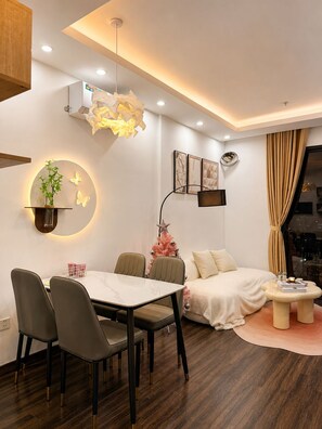 A modern hotel room with a dining area, a bed, and a view of the city. - X-Stay Sweet (Hai Phong)