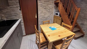 Eine kleine Küche mit Holztisch und -stühlen, einer eingebauten Mikrowelle und einer Wand mit Steinoptik.