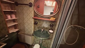Ein Badezimmer mit einem grünen Waschbecken, einer Toilette, einer Dusche und einem Spiegel.