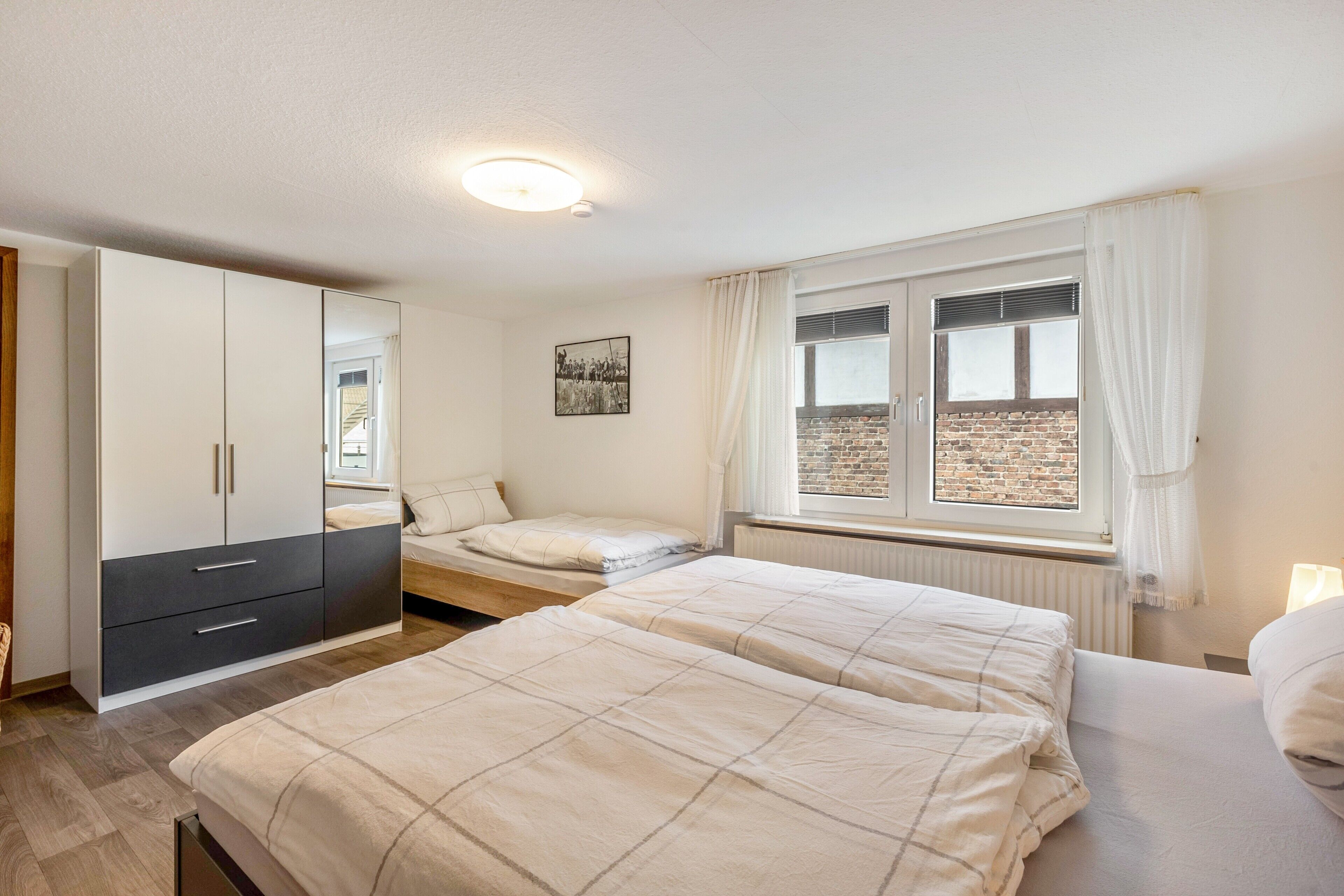 A bedroom with a bed, a wardrobe, a window with curtains, and a radiator.