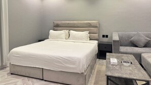 Une chambre moderne avec un lit, un canapé gris, une petite table et un appareil de climatisation.