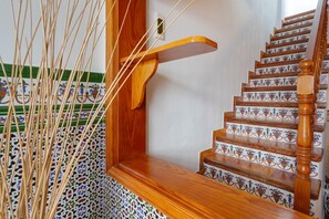 Uma escadaria de madeira com corrimão de madeira e uma parede decorativa com azulejos estampados.