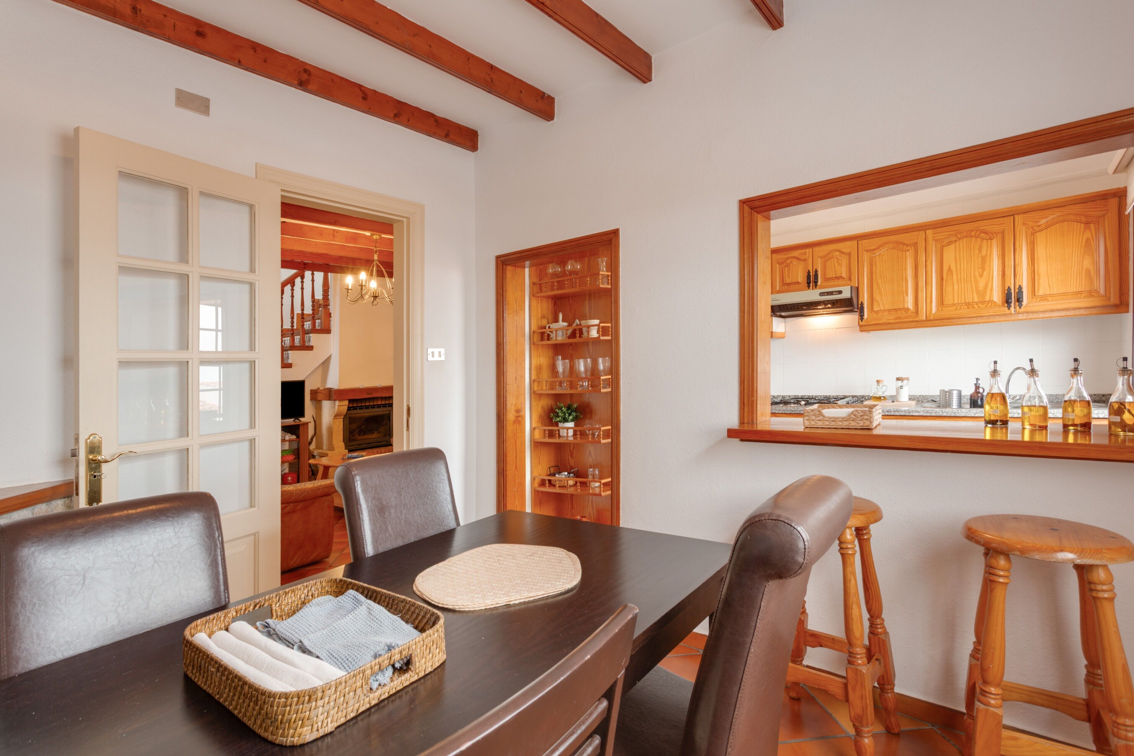 A dining area with a wooden table, chairs, and a kitchen visible through an open door.