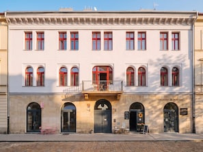 A building with a symmetrical facade, multiple windows with red frames, and a central entrance with a balcony. - TurnKey | Florenc Apartment with Terrace II (Praha 8)