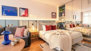 Ett modernt hotellrum med en stor säng, en soffa, ett matbord och en spegel.