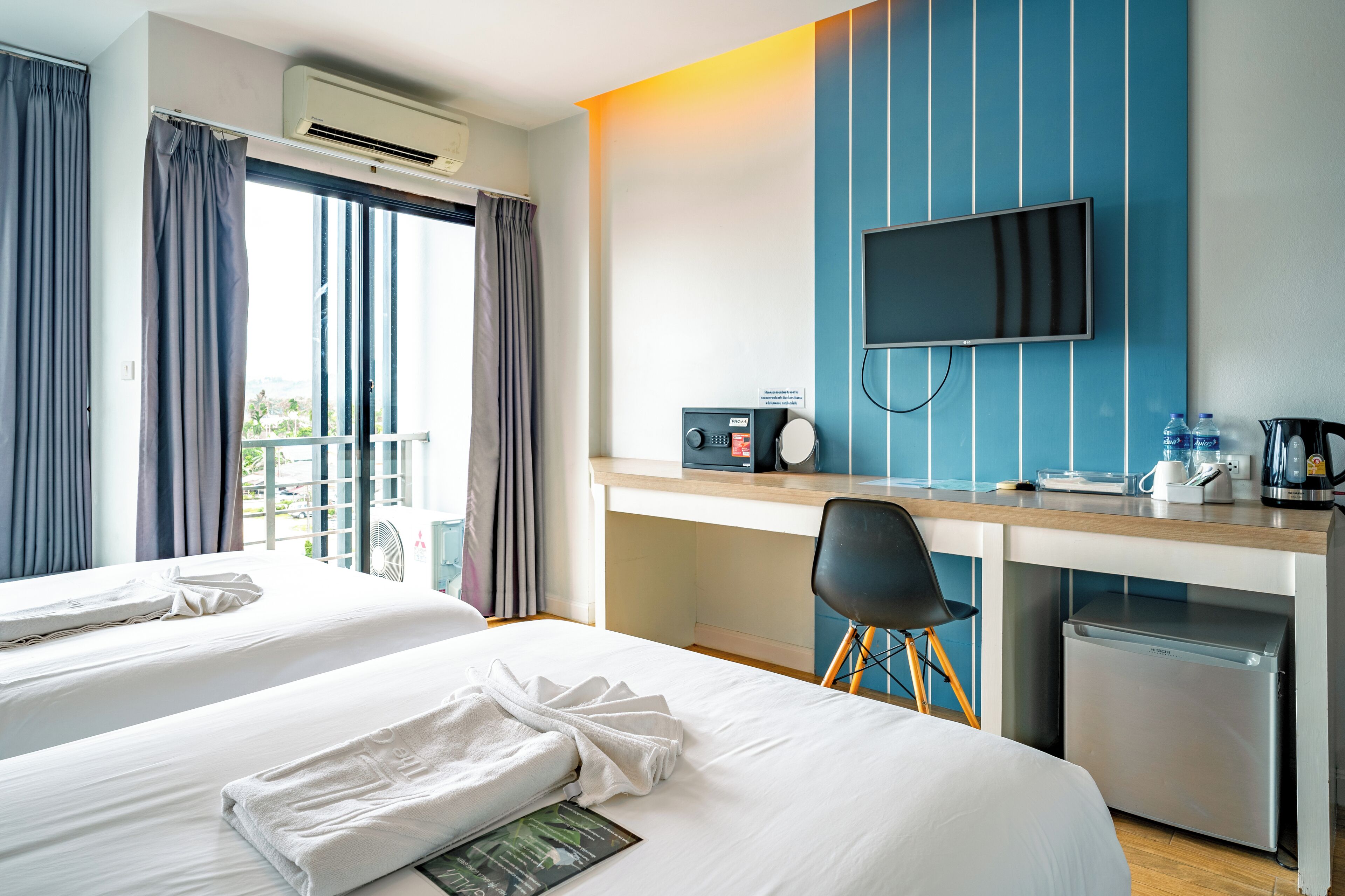 A hotel room with two beds, a desk with a TV, a coffee maker, and a mini-fridge.