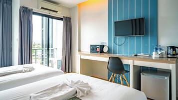 A hotel room with two beds, a desk with a TV, a coffee maker, and a mini-fridge.