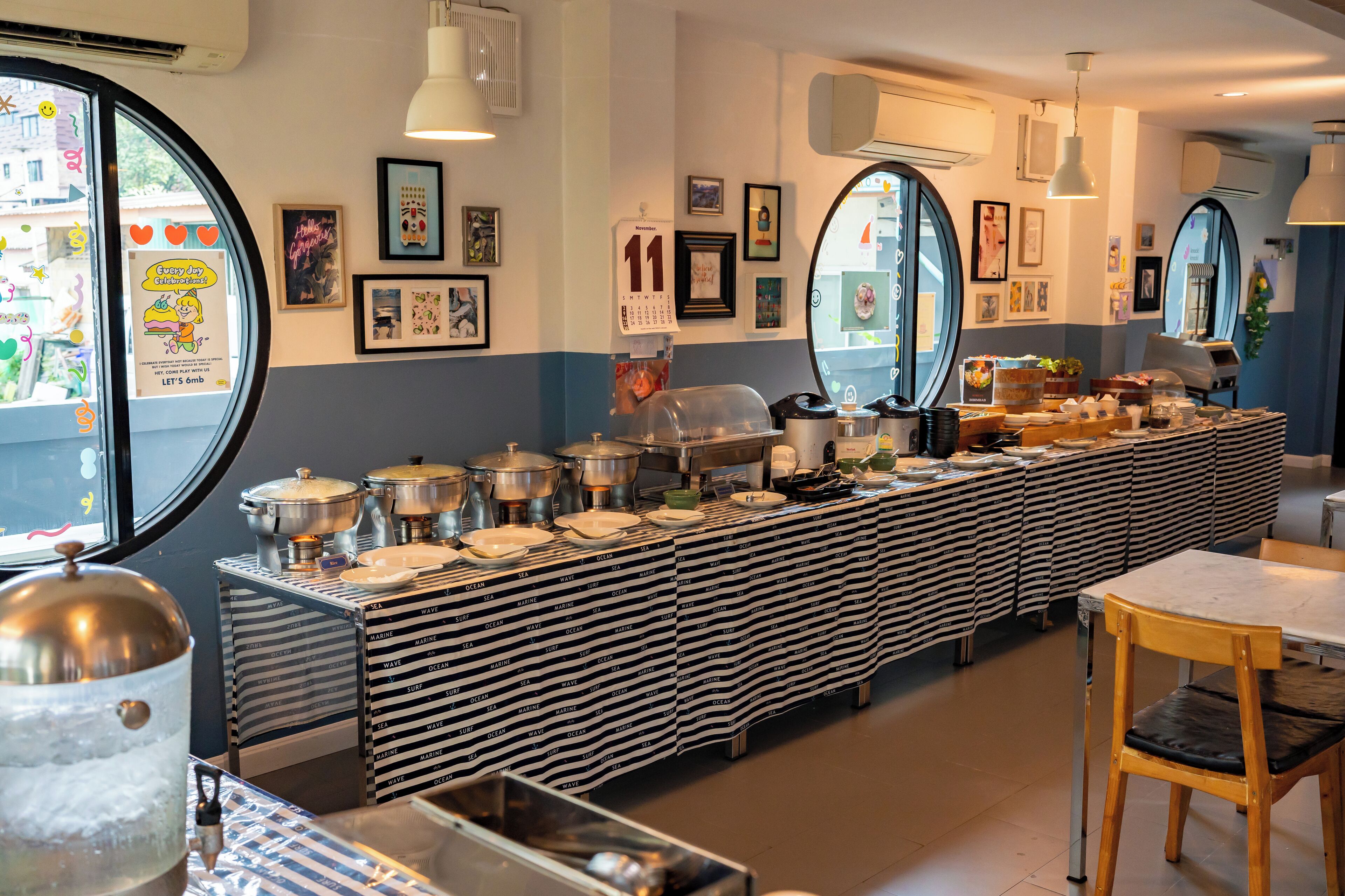 Un'area buffet con diverse postazioni di servizio, un ampio specchio e quadri appesi alle pareti.