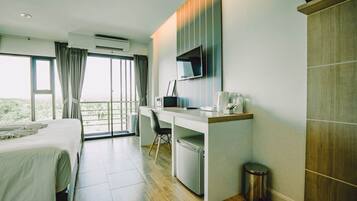 Habitación de hotel con cama, escritorio con computadora, televisor y vista al exterior.