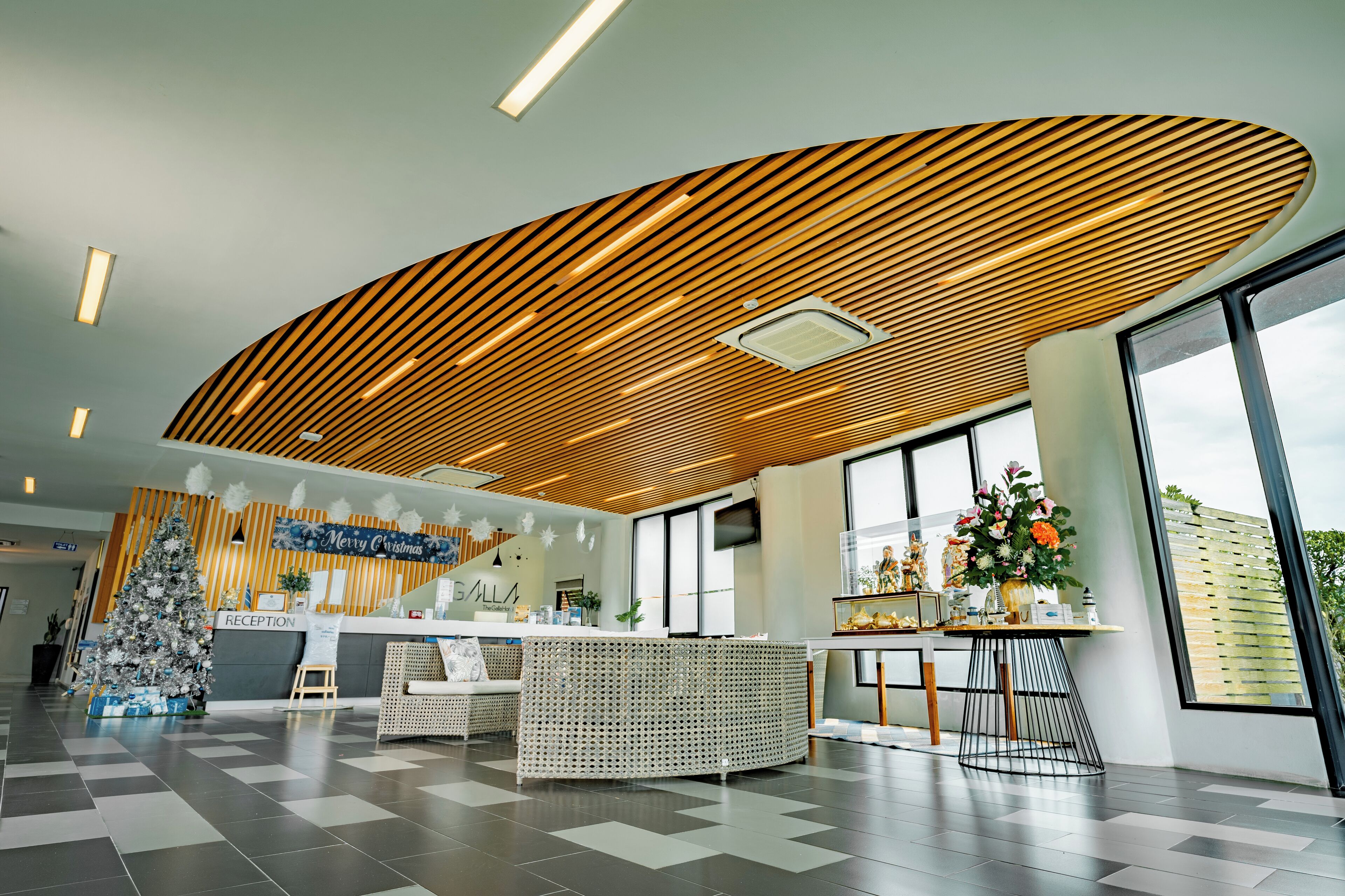 A modern reception area with a Christmas tree, a reception desk, and a large window providing a view of the outdoors.