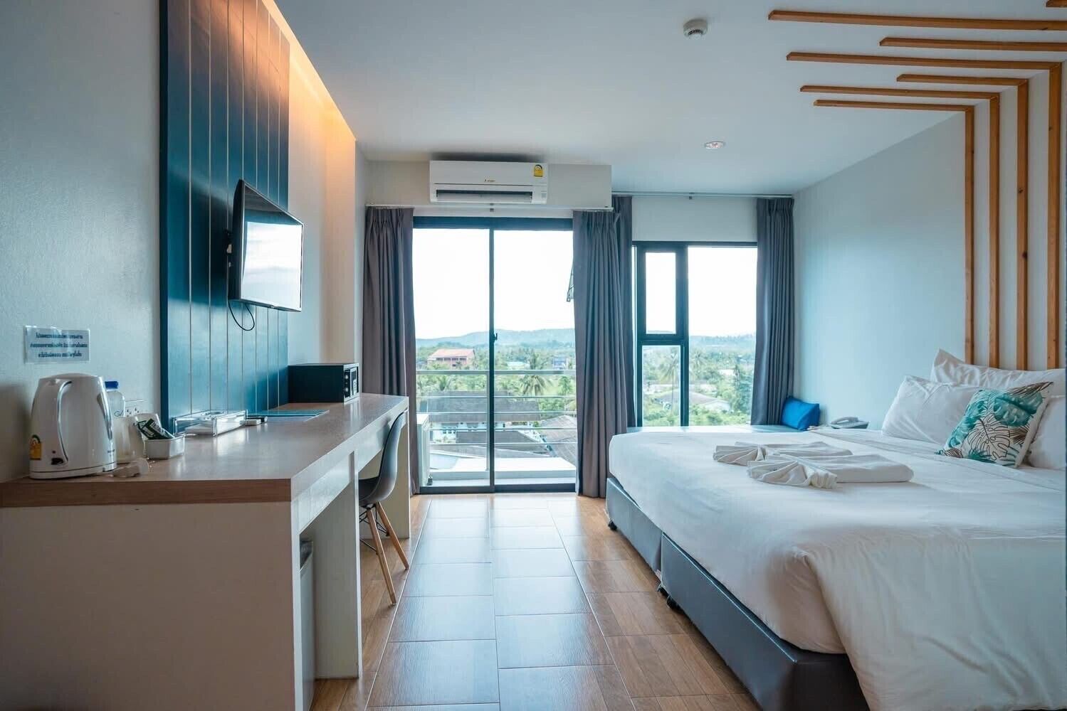 Un moderno cuarto de hotel con una cama grande, un escritorio con silla, un televisor de pantalla plana y vistas a la ciudad a través de las ventanas.