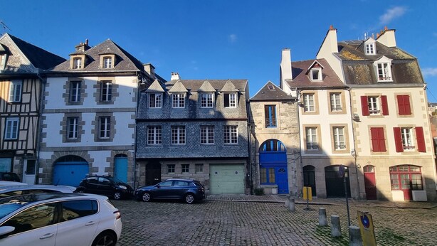 A cobblestone street with historic buildings, including a building with a blue door and another with red shutters. - Bright apartment with terrace in the heart of Morlaix (Morlaix)