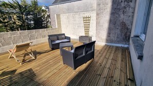 A wooden deck with wicker furniture and a small table. - Bright apartment with terrace in the heart of Morlaix (Morlaix)