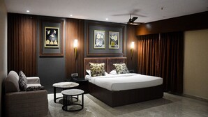 A modern bedroom with a large bed, a nightstand, a chair, and a small table. - HOTEL HELLO JEYPORE (Jaypur)