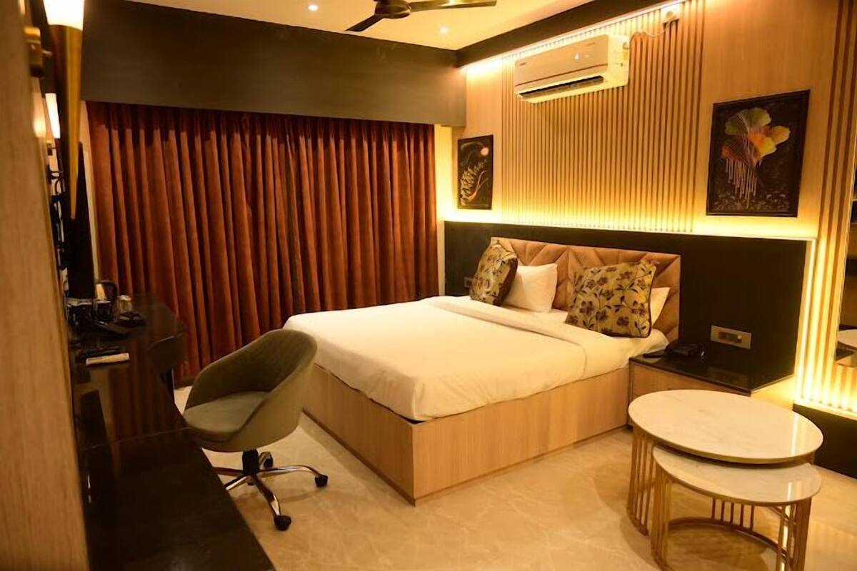 A modern bedroom with a bed, a desk, a chair, and a small round table.