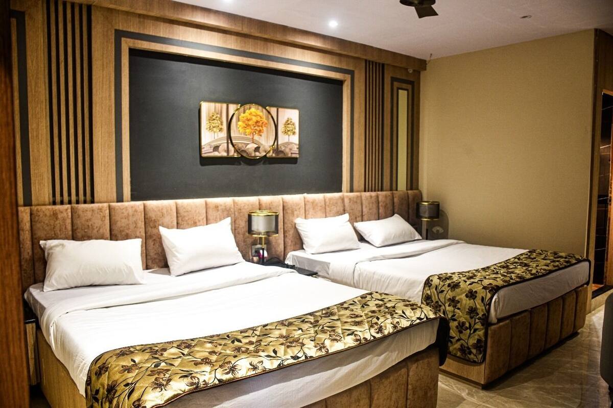 A hotel room with two beds, a large artwork above the headboard, and a wooden panel design on the walls.