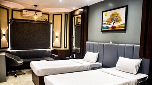 A hotel room with two beds, a desk with a chair, a large mirror, and a painting of a tree on the wall. - HOTEL HELLO JEYPORE (Jaypur)