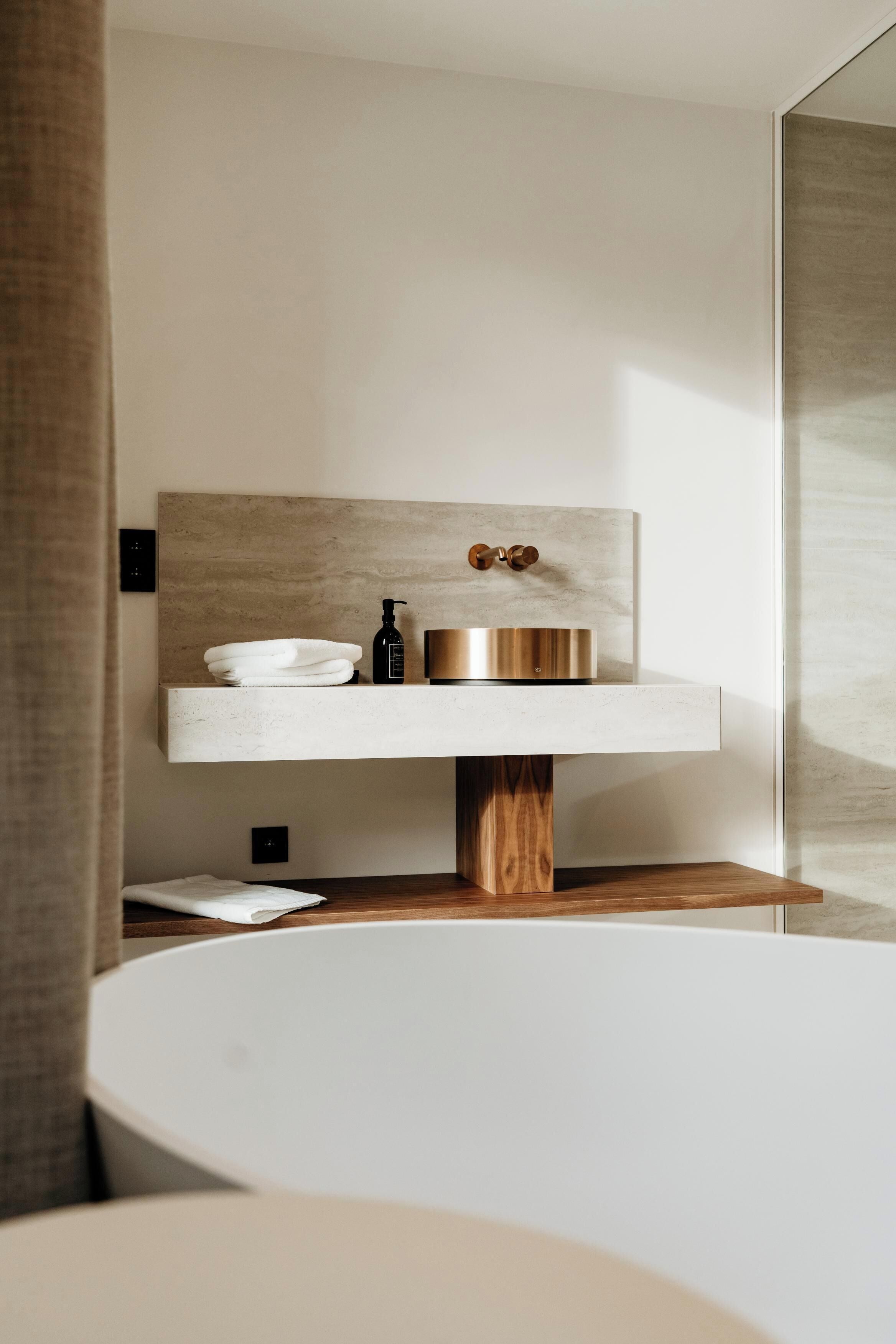 A modern bathroom with a minimalist design, featuring a large bathtub, a wooden vanity with a sink, and a mirror.