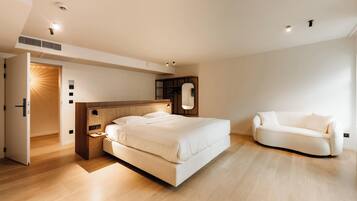 Een moderne slaapkamer met een groot bed, een nachtkastje, een inbouwkast en een witte bank.