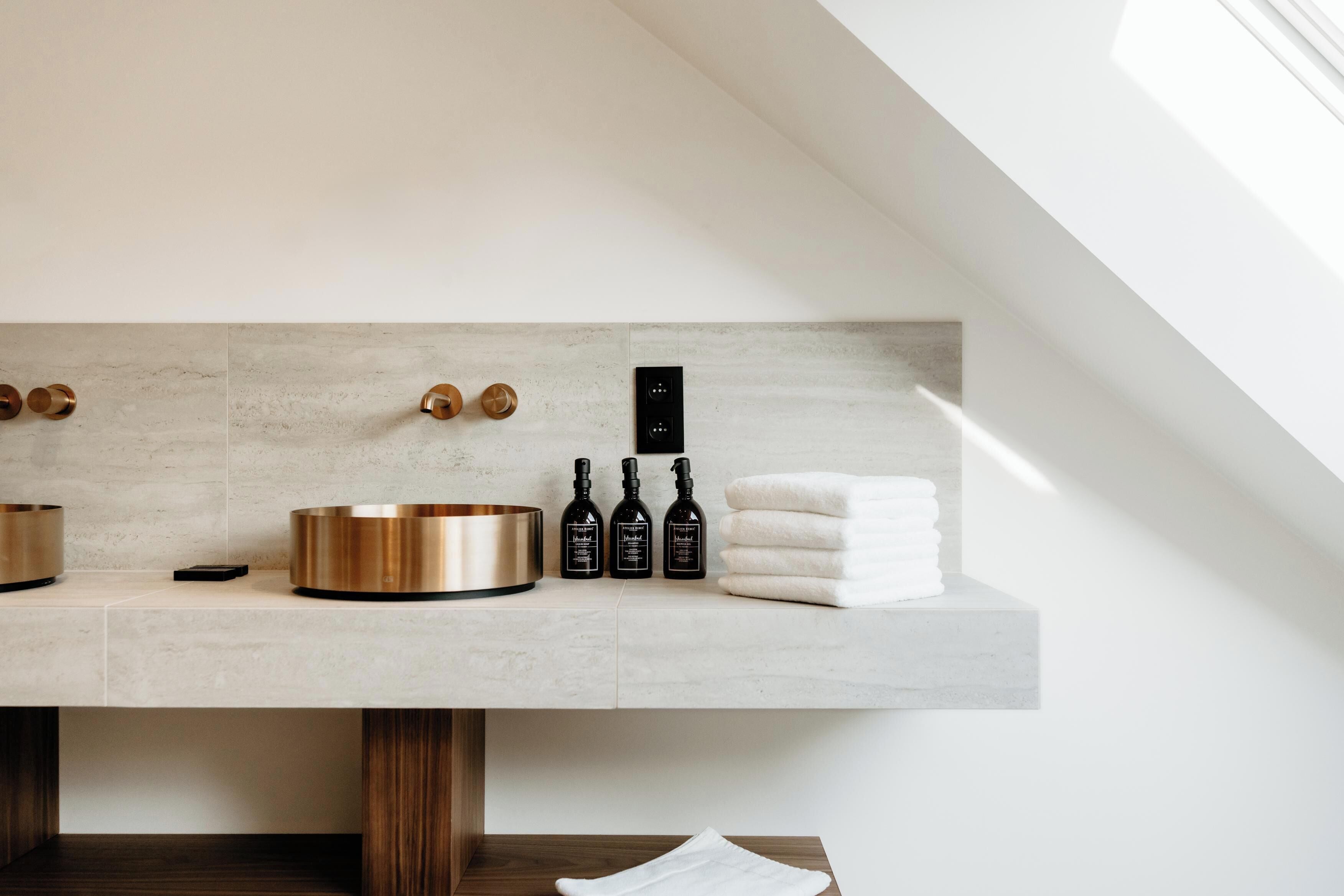 Un baño moderno con diseño minimalista, que cuenta con un lavamanos grande, un calefactor empotrado y artículos de aseo ordenados.