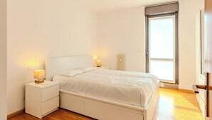 Een moderne slaapkamer met een bed, nachtkastjes en een radiator.